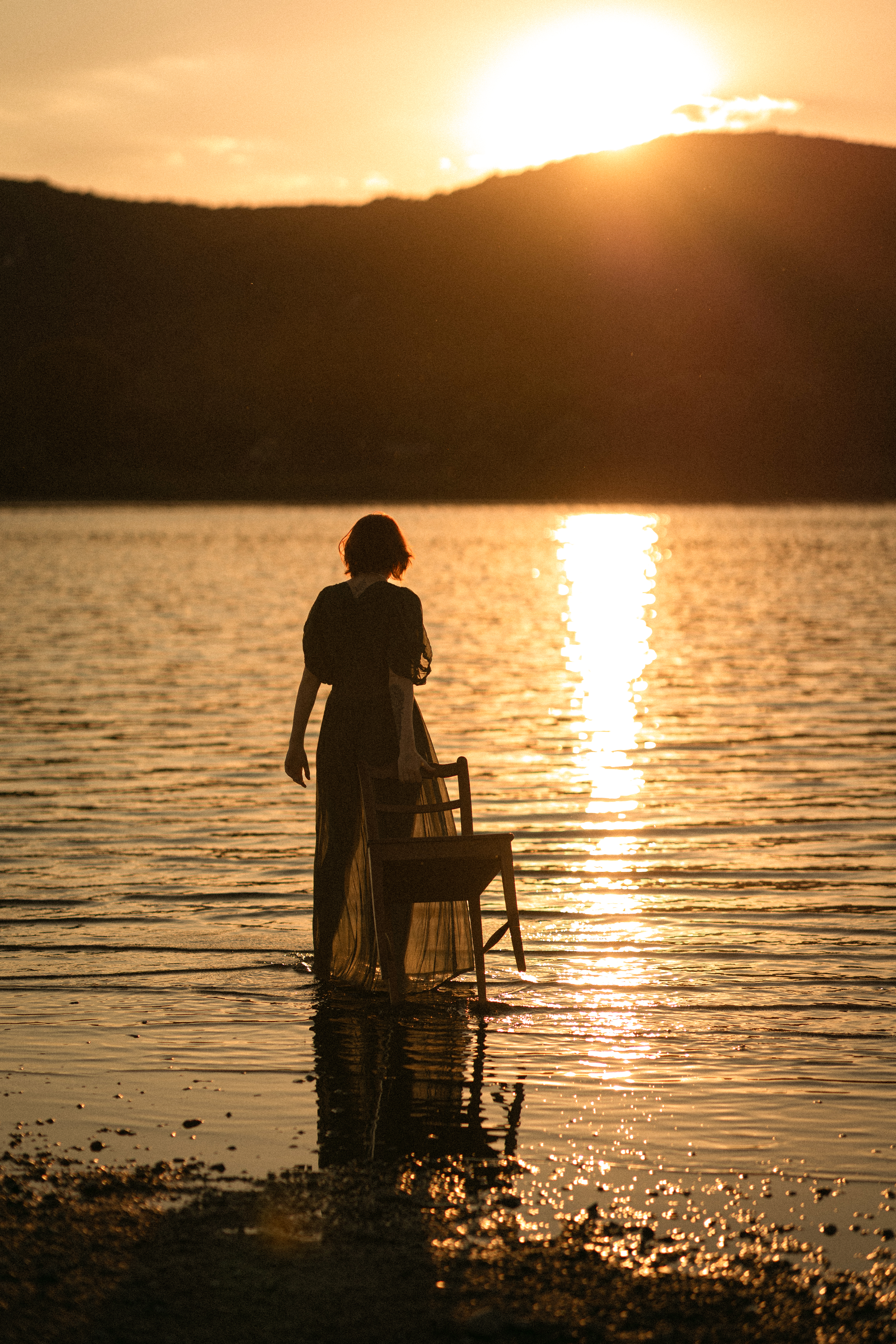 A figure standing in dark water at last light